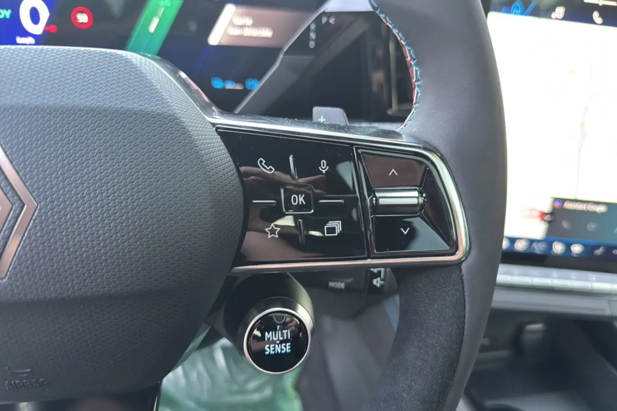 Gros plan sur le volant du Renault Austral New 200 Esprit Alpine Tpano 2025 noir étoilé, avec commandes multifonctions et bouton Multi-Sense.