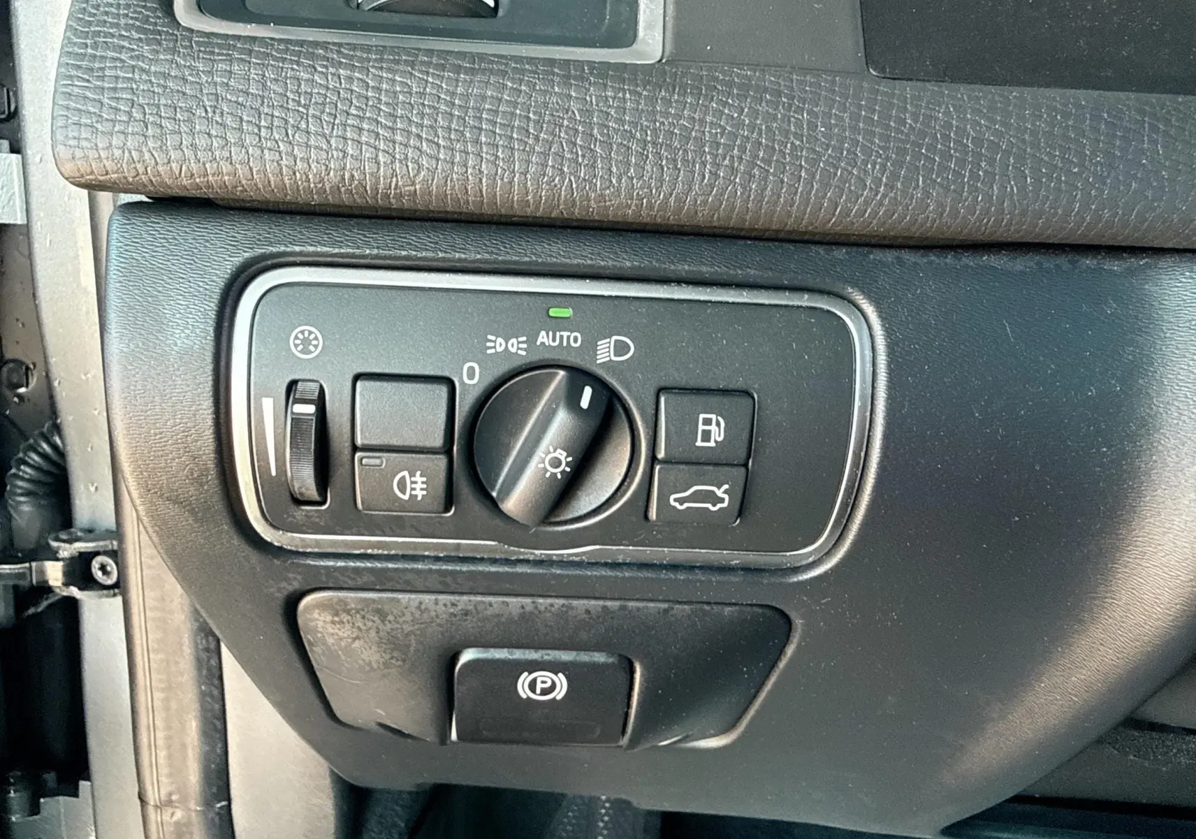 Gros plan sur les commandes d'éclairage et frein à main électrique du tableau de bord du Volvo XC60 D4 gris 2016.