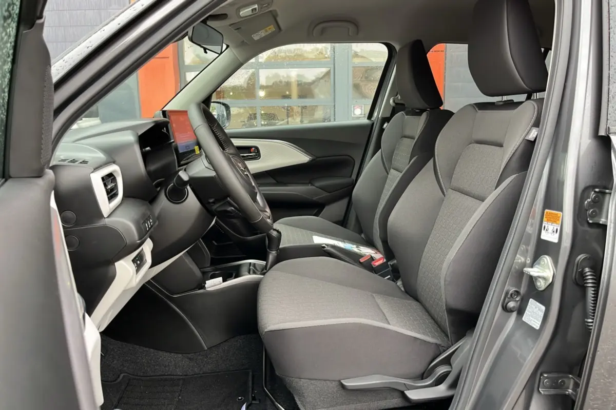 Vue côté conducteur de l'intérieur gris d'une Suzuki Swift 2025 avec sièges tissu et tableau de bord moderne.
