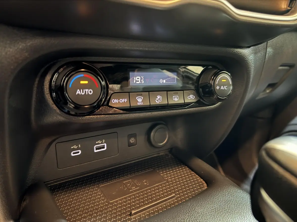 Détail de la console centrale noire du Nissan Juke 2025, montrant la climatisation automatique et ports USB.