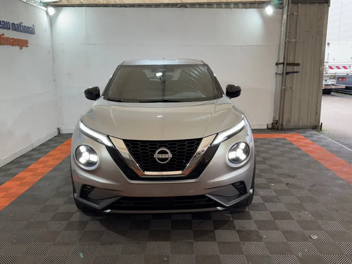 Vue frontale d'un Nissan Juke gris clair avec phares LED allumés dans un garage.