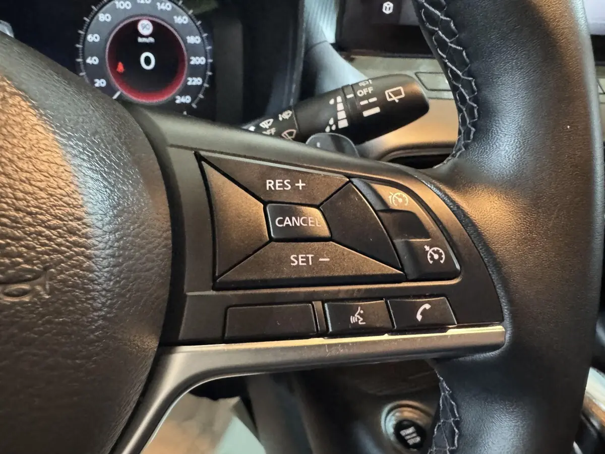 Gros plan sur le côté droit du volant cuir alu du Nissan Juke gris clair, avec commandes de régulateur de vitesse et appels.