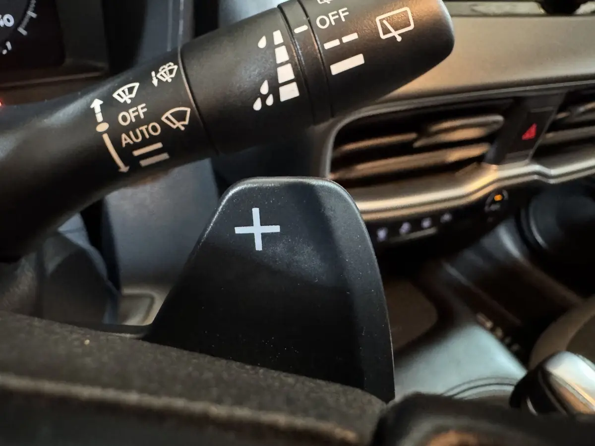 Gros plan sur la palette de changement de vitesse droite noire dans l'habitacle gris du Nissan Juke 2025.