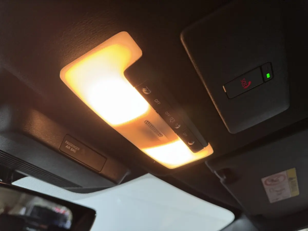 Vue intérieure du plafond du Nissan Juke gris clair 2025, avec éclairage intérieur et bouton SOS allumé.