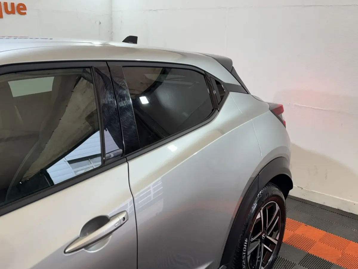 Vue latérale côté gauche du Nissan Juke gris clair 2025, mettant en valeur la ligne arrière et les jantes noires.