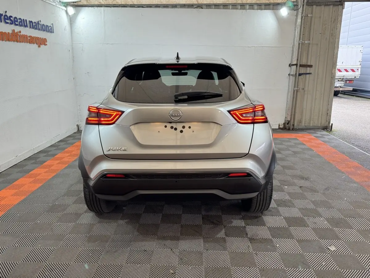 Vue arrière d'un Nissan Juke gris clair 2025 avec feux LED allumés dans un garage éclairé.