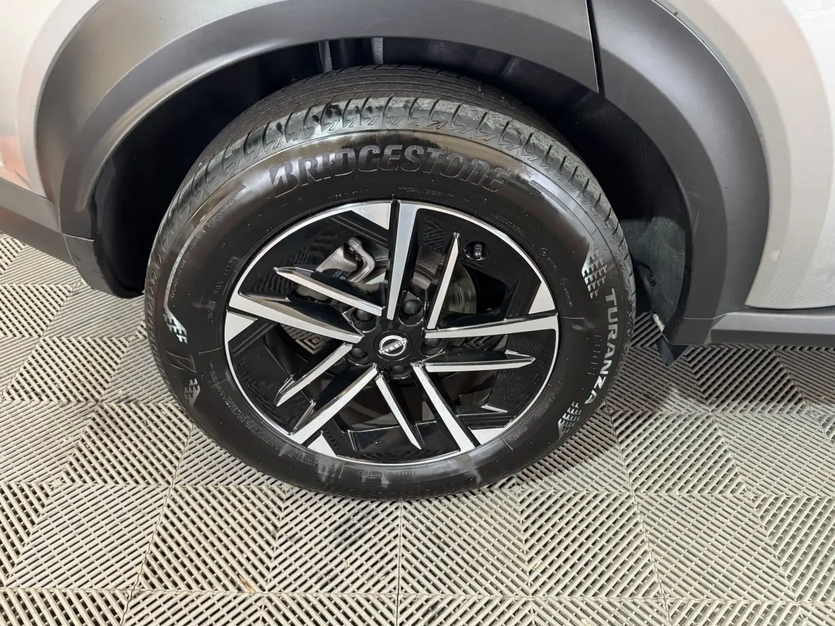 Gros plan sur la roue avant droite gris clair du Nissan Juke 2025 avec jante noire et argentée au design moderne.