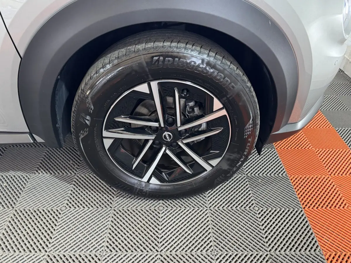 Gros plan sur la roue avant droite gris clair du Nissan Juke 2025 avec jante alliage noir et argentée.