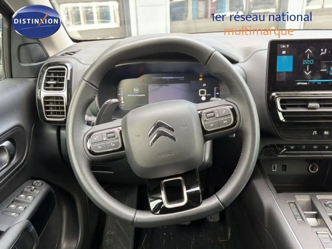 Vue intérieure centrée sur le volant du Citroën C5 Aircross Hybrid 2025 avec tableau de bord numérique et écran tactile.