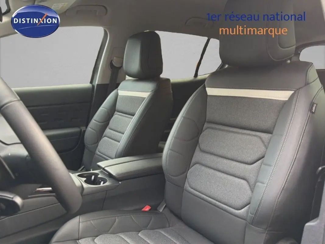 Vue intérieure sur les sièges avant en cuir et tissu gris du Citroën C5 Aircross Hybrid 2025, avec accoudoir central.