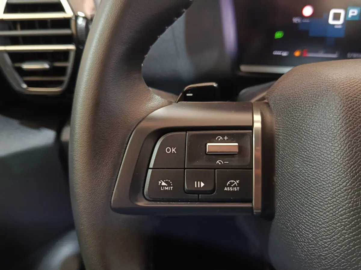 Gros plan sur les commandes à gauche du volant cuir noir du Citroën C4 X 2023, avec boutons multifonctions.