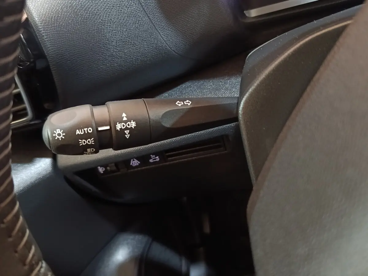 Gros plan sur la commande des feux et clignotants côté gauche du volant dans l’habitacle noir du Citroën C4 X 2023.