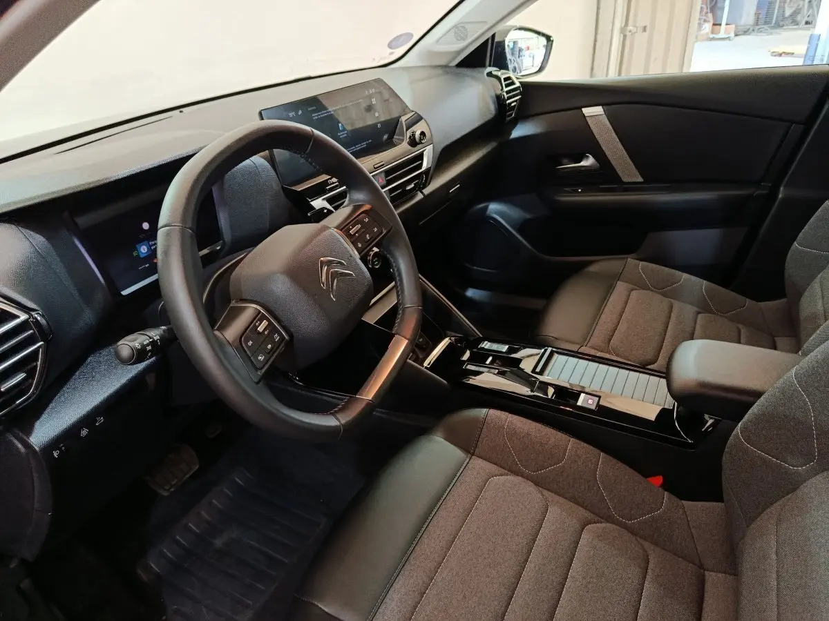 Intérieur de la Citroën C4 X noir, vue côté conducteur, volant cuir multifonctions et écran tactile central.