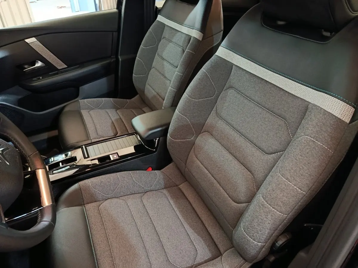 Vue intérieure côté conducteur du Citroën C4 X 2023, sièges tissu gris avec appuie-tête noir et accoudoir central.