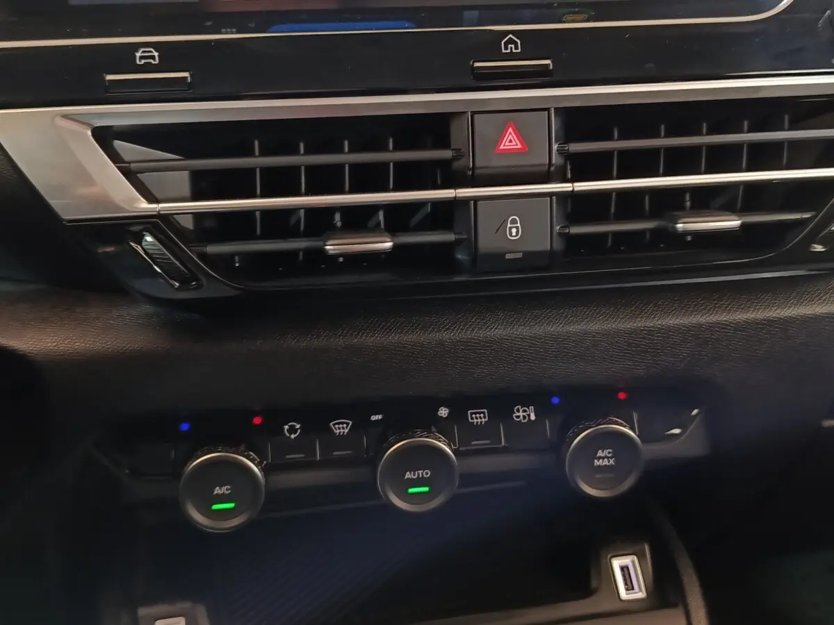Vue rapprochée du tableau de bord central noir du Citroën C4 X 2023, avec commandes climatisation et prises USB visibles.