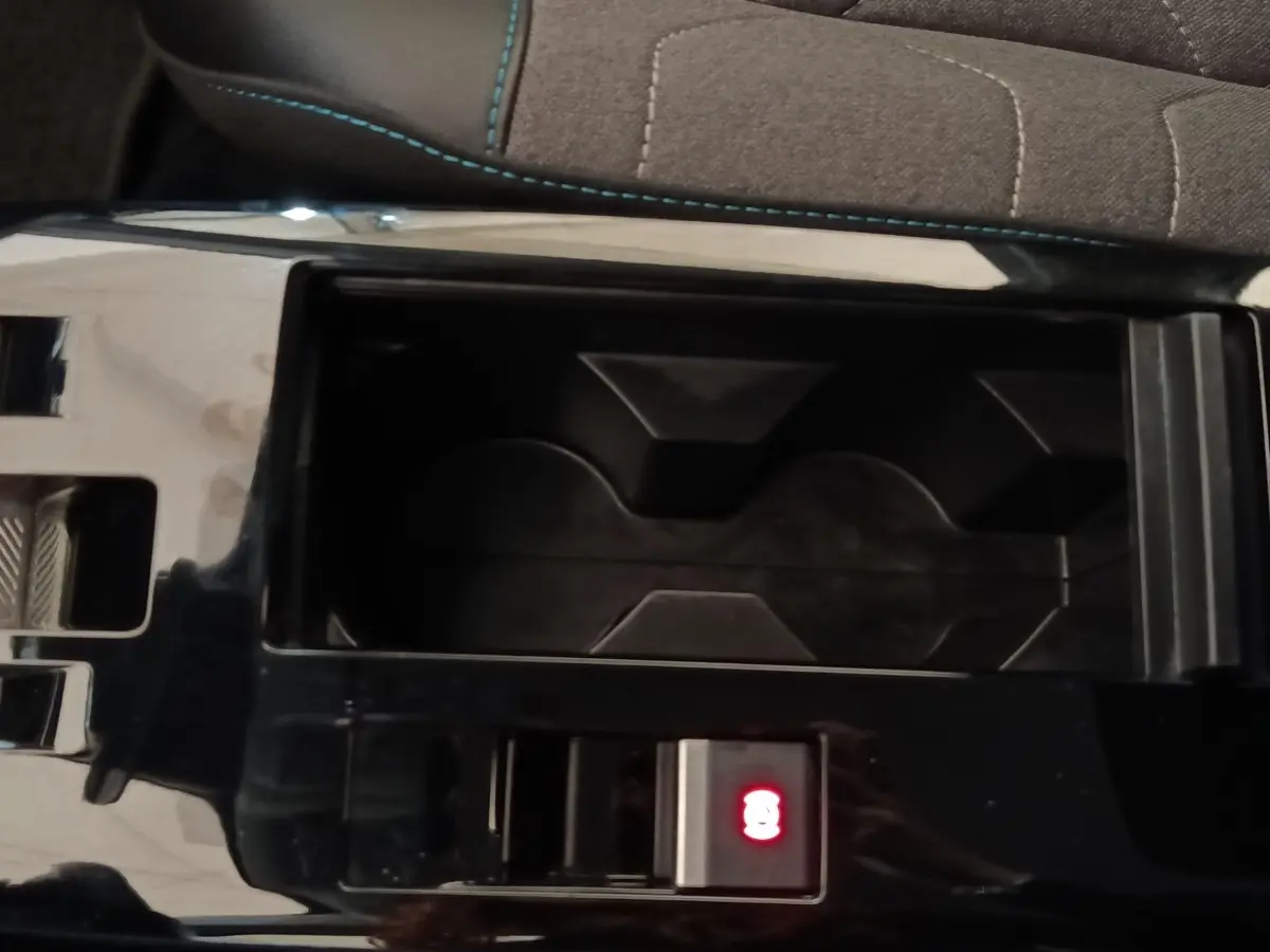 Gros plan sur la console centrale noire du Citroën C4 X avec bouton de frein à main électrique illuminé en rouge.