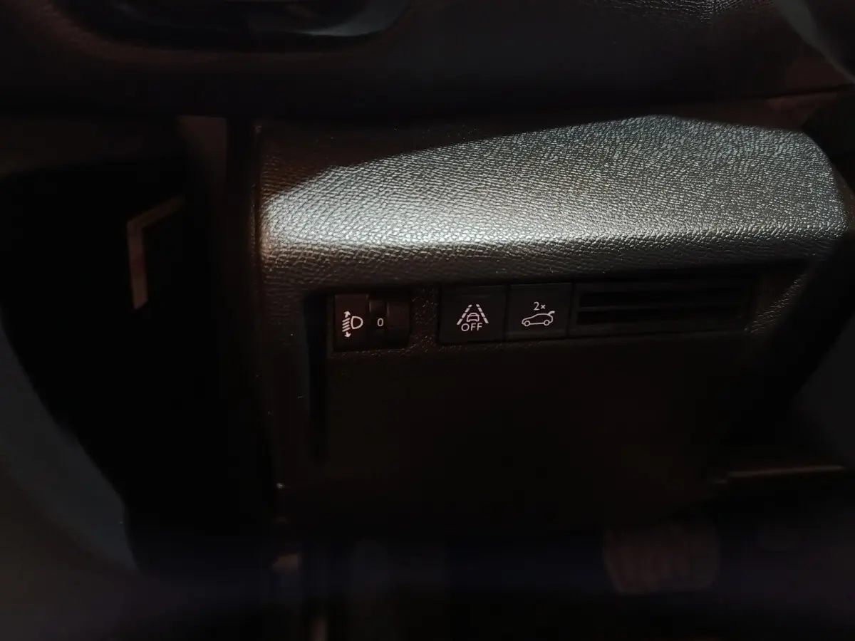 Détail des commandes d'assistance et réglage des phares sur la gauche du tableau de bord noir du Citroën C4 X.