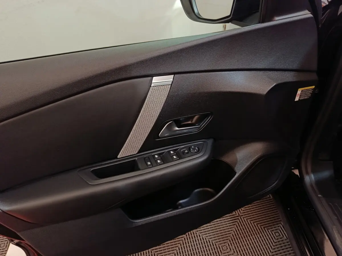 Vue intérieure du panneau de porte avant gauche noir de la Citroën C4 X 2023 avec commandes électriques et insert décoratif gris.