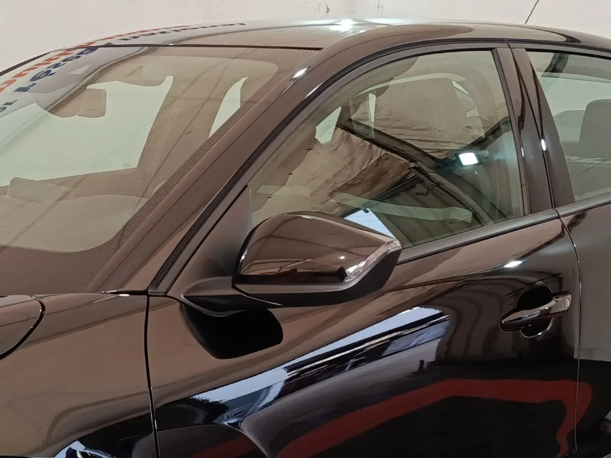 Vue latérale gauche rapprochée d'une Citroën C4 X noire 2023 avec rétroviseur ton caisse et poignée de porte visible.