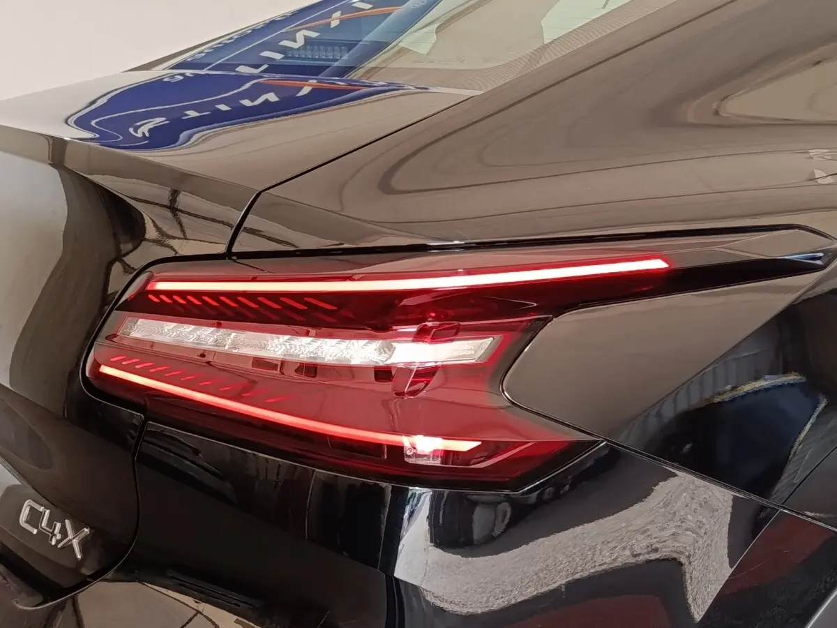 Gros plan sur le feu arrière droit rouge et blanc d'une Citroën C4 X noire, avec logo C4 X visible sur la carrosserie.