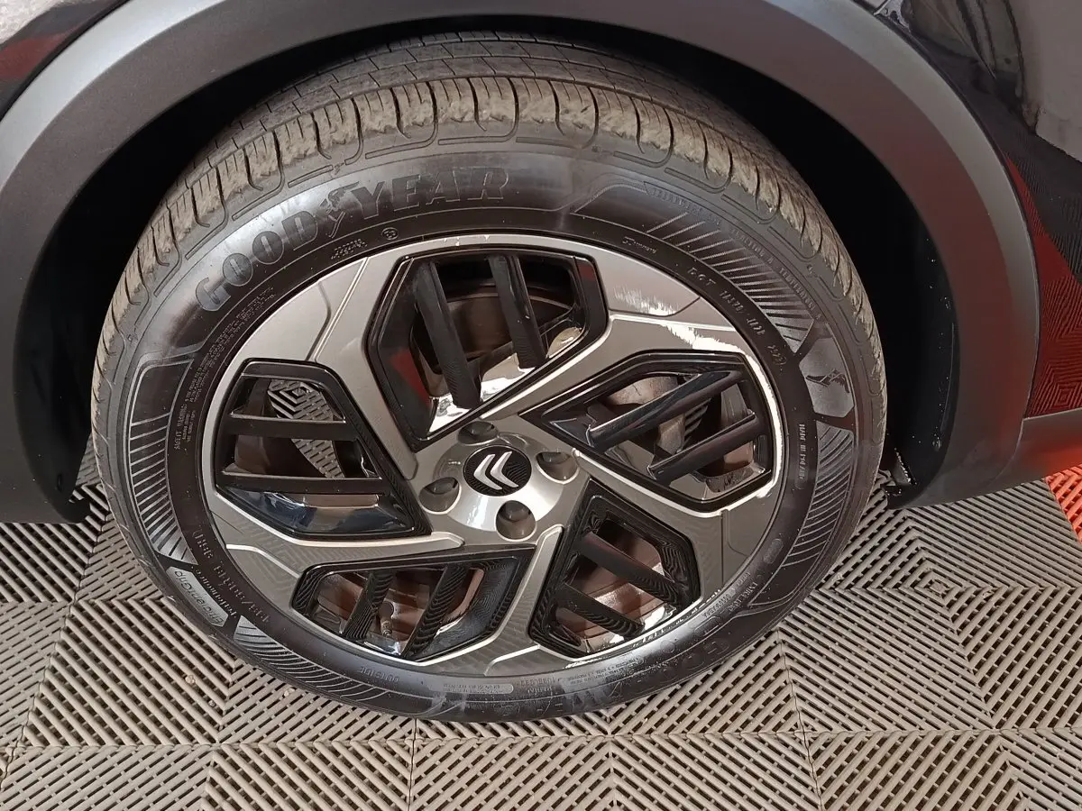 Gros plan sur la roue avant droite noire d’une Citroën C4 X 2023 avec jante alliage et pneu Goodyear.