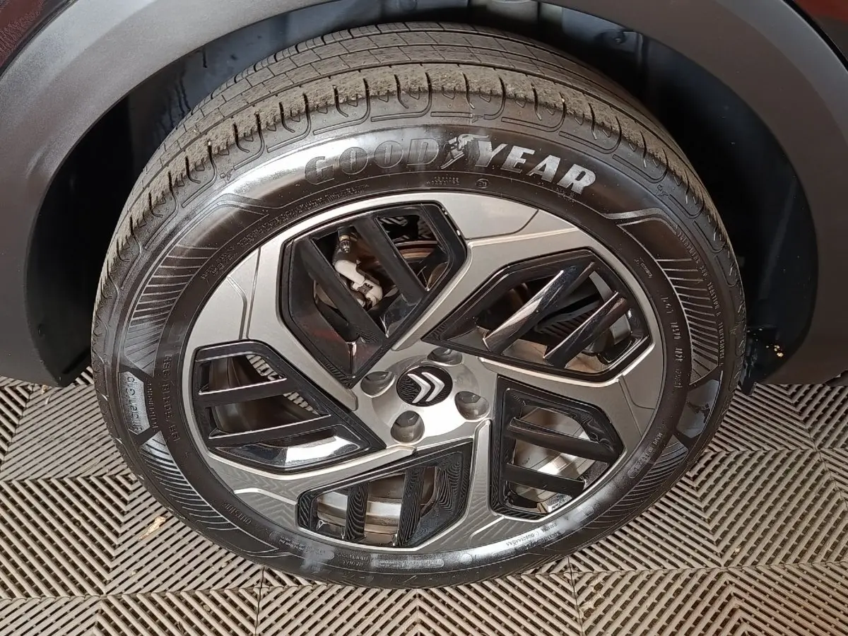 Gros plan sur la roue avant gauche du Citroën C4 X noir, avec jante alliage au design géométrique et pneu Goodyear.