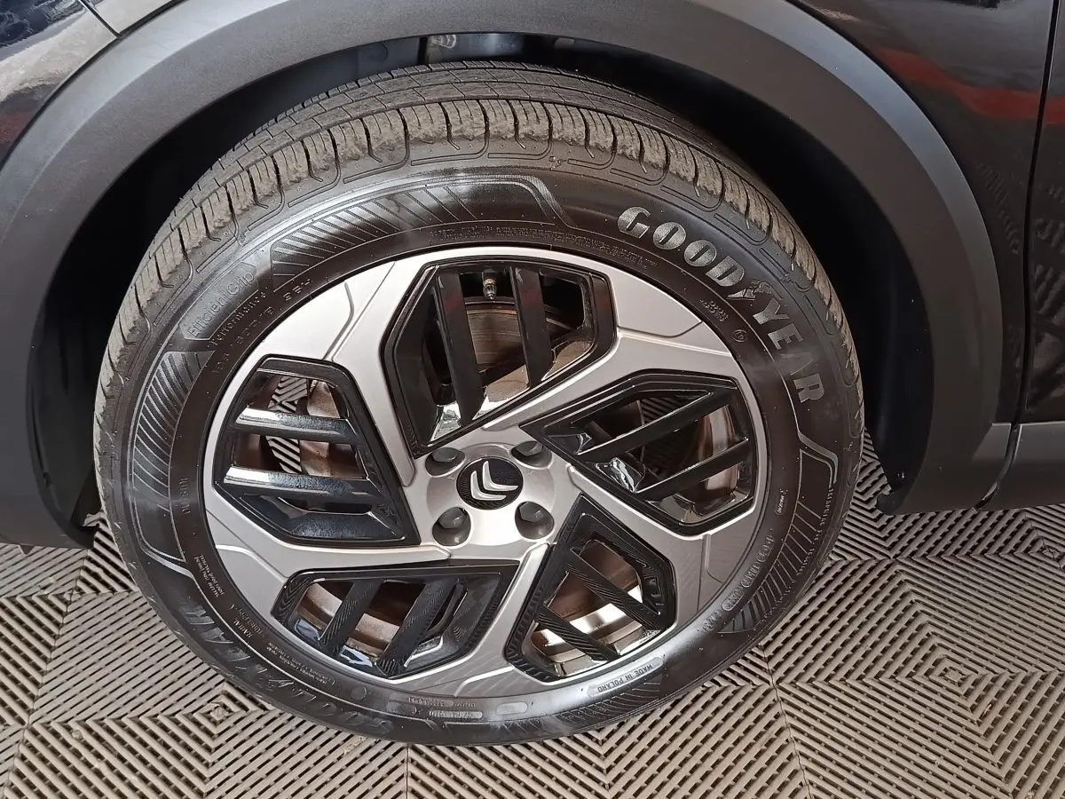 Gros plan sur la roue avant gauche noire d’une Citroën C4 X avec jante alu bicolore et pneu Goodyear.
