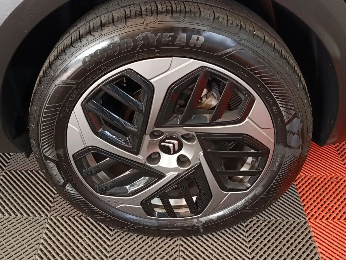 Gros plan sur la roue avant droite d'une Citroën C4 X noire, avec jante alliage au design géométrique bicolore.