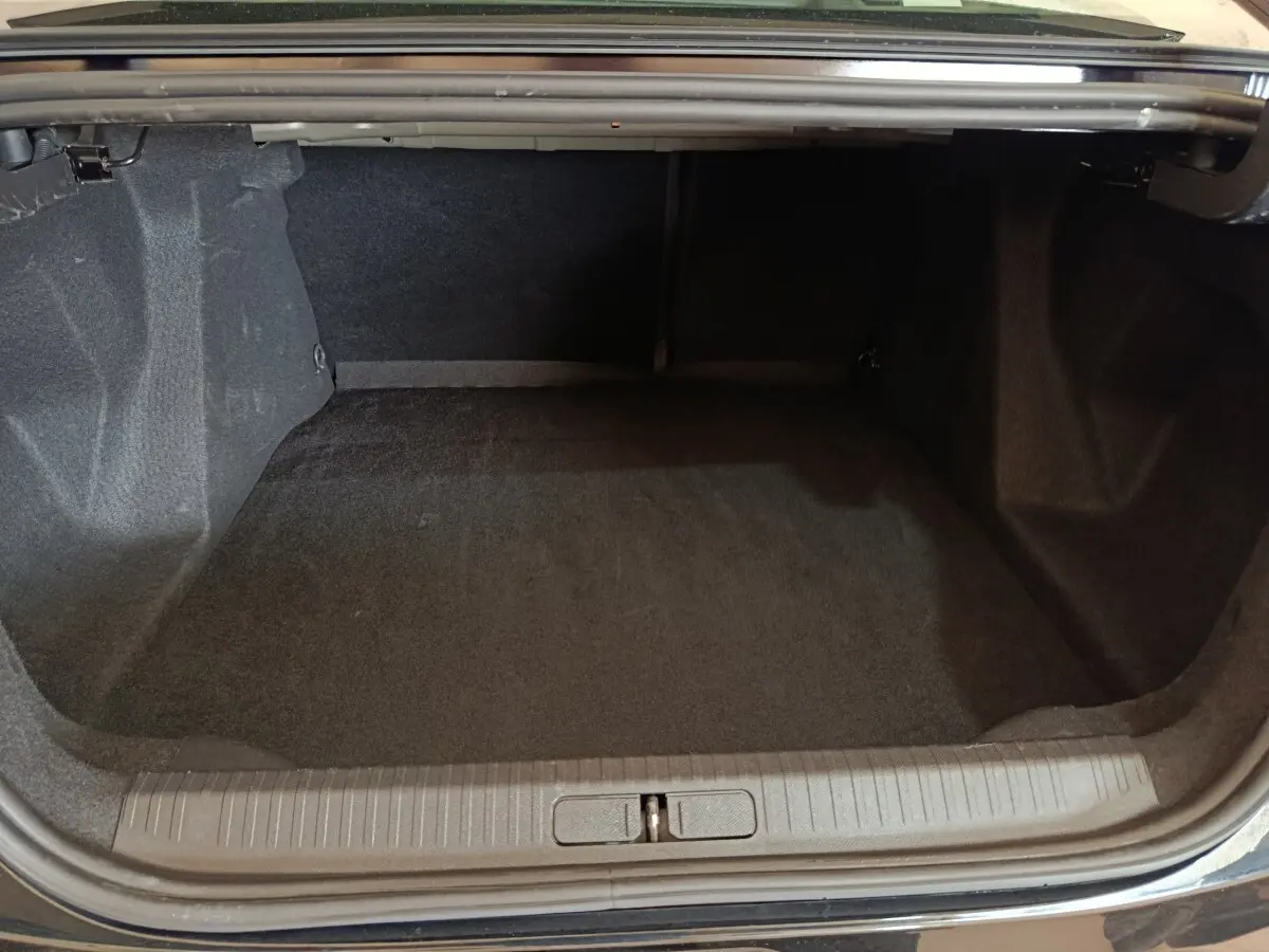 Coffre ouvert de la Citroën C4 X noire, vue intérieure montrant un espace de chargement propre et spacieux.