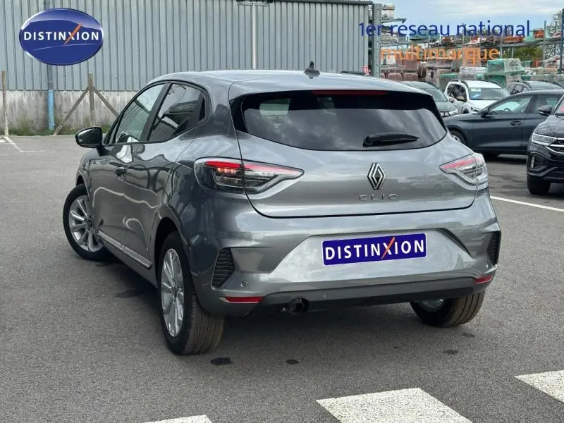 Vue 3/4 arrière d'une Renault Clio gris métallisé 2025 avec feux arrière LED et logo distinctif sur parking.