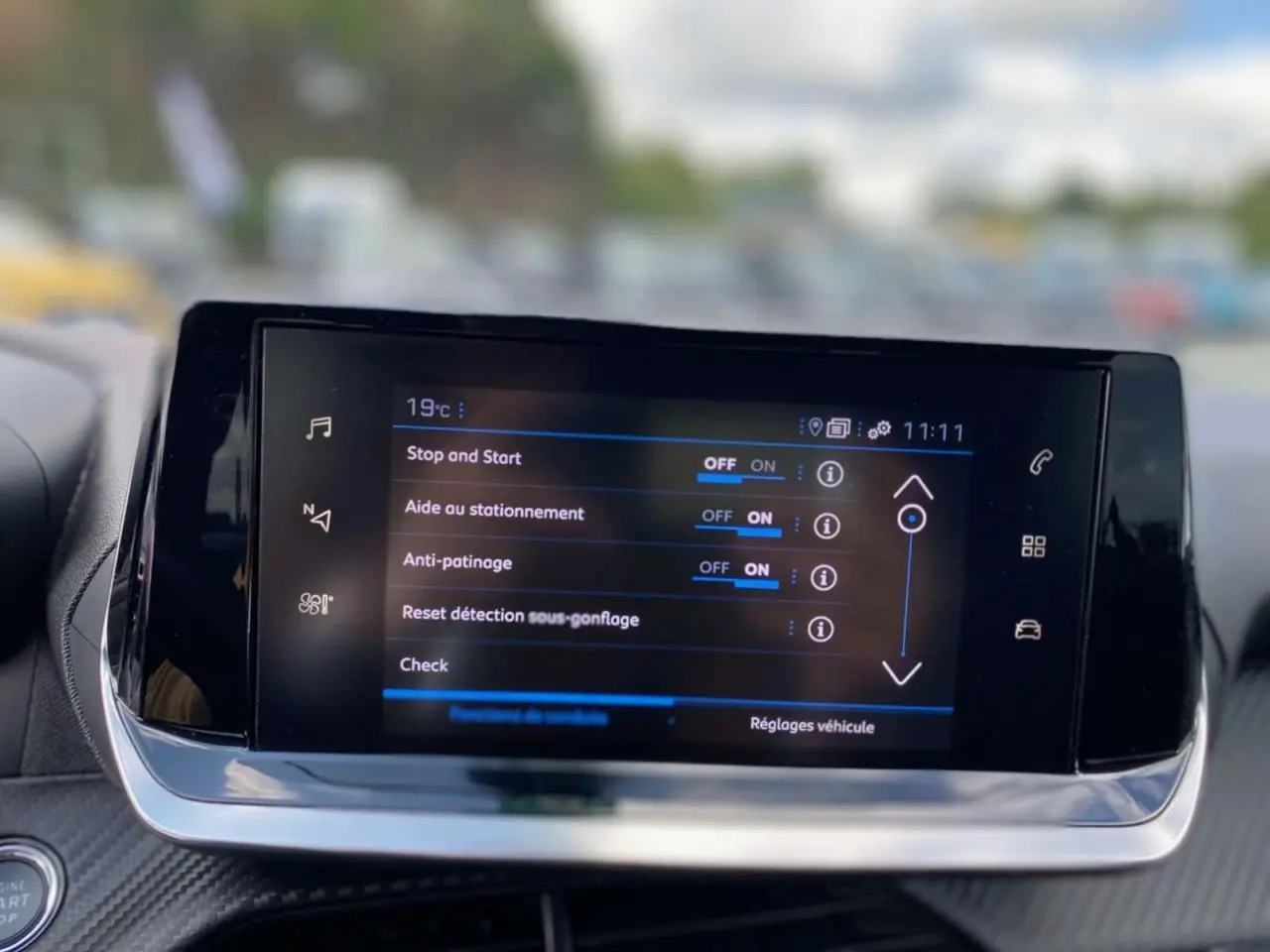 Écran tactile central de la Peugeot 208 noir affichant les réglages d'aide à la conduite en intérieur.