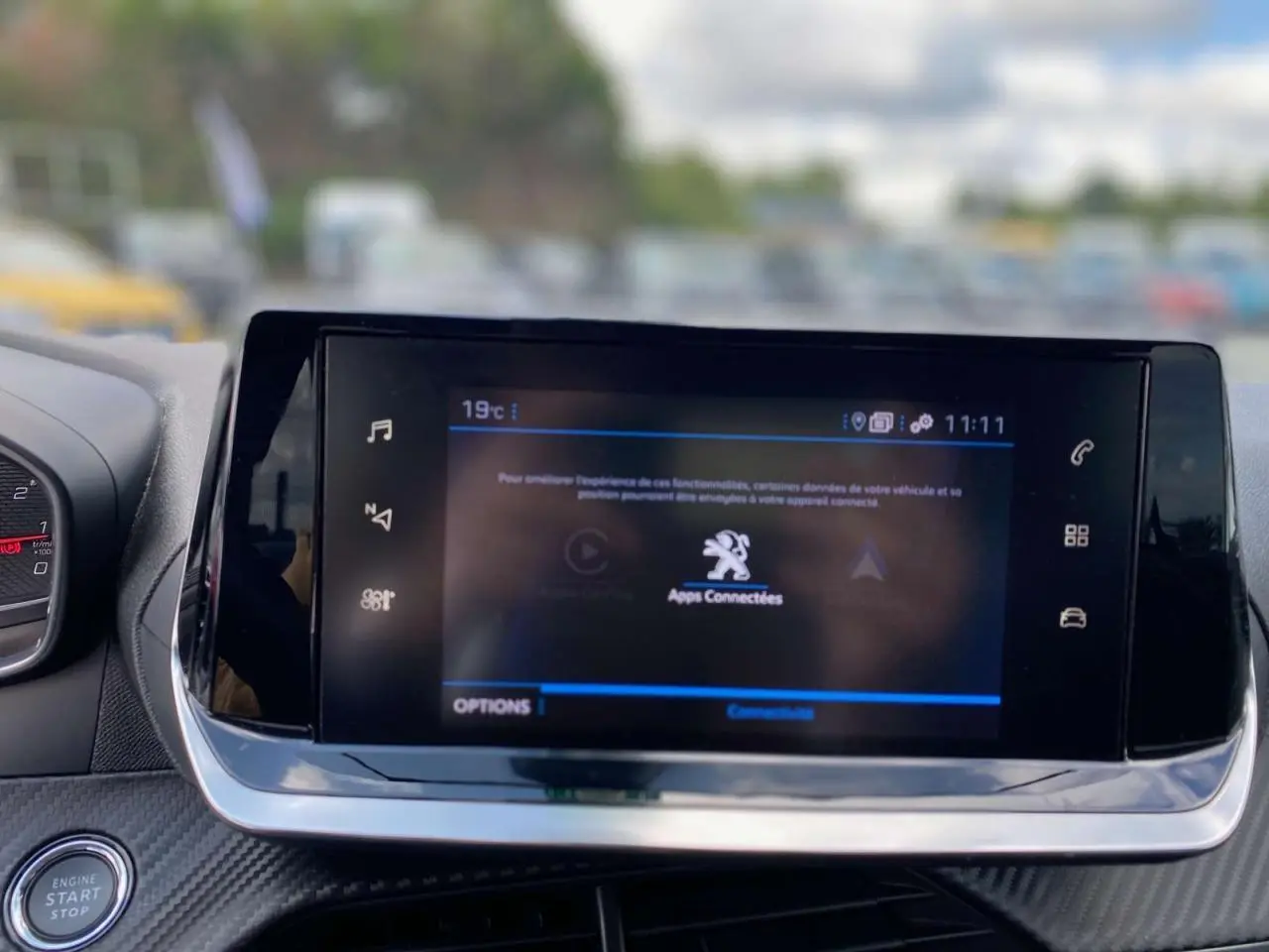 Écran tactile central de la Peugeot 208 2021 en noir, affichant les applications connectées, avec bouton start/stop visible.
