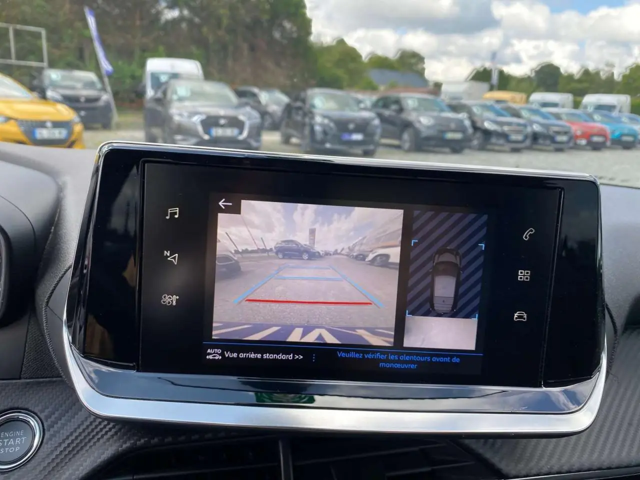 Écran tactile de la Peugeot 208 noire montrant la caméra de recul et la vue 360° du stationnement.