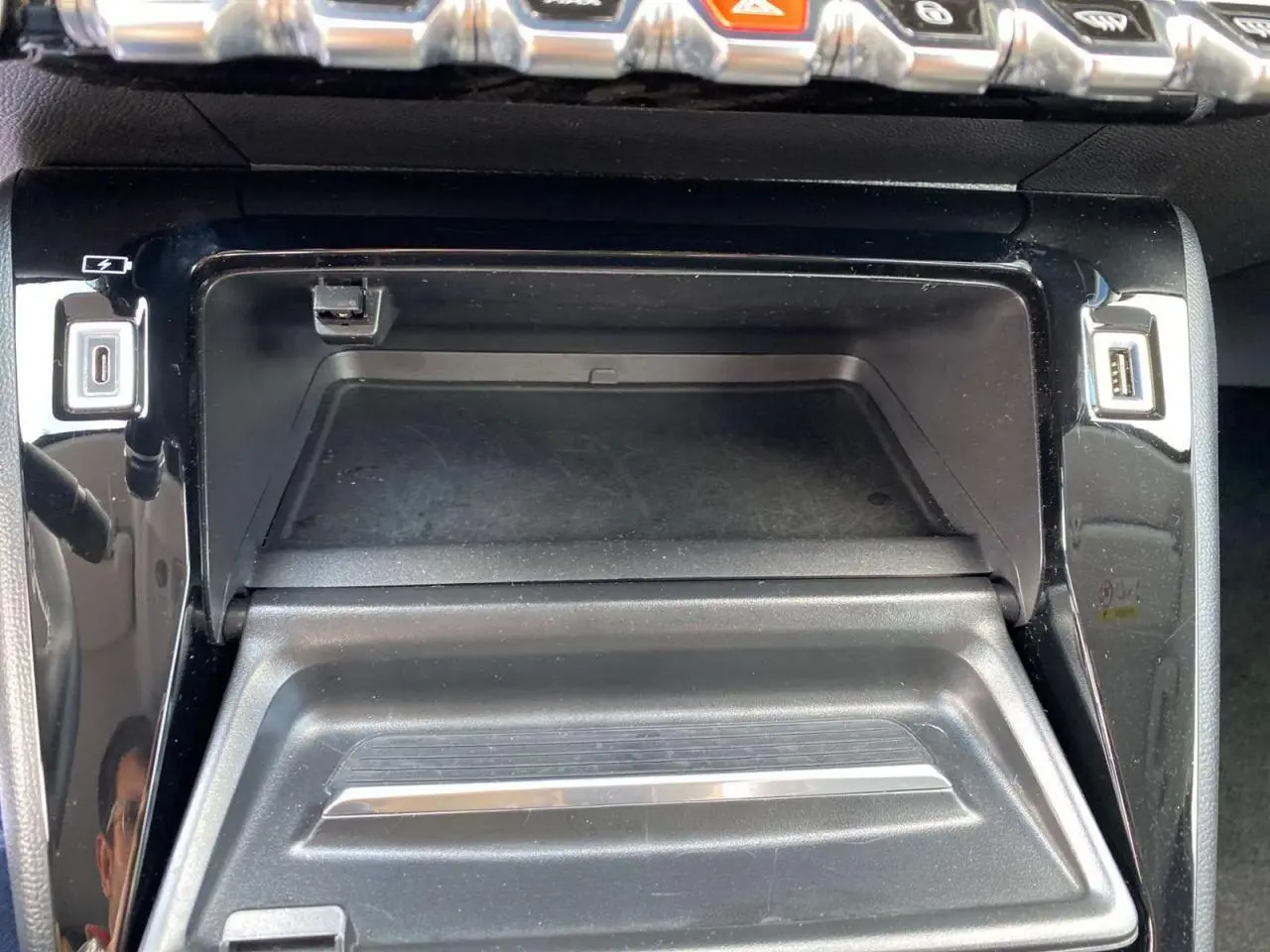 Gros plan sur la console centrale noire de la Peugeot 208 2021 avec ports USB et finition brillante.