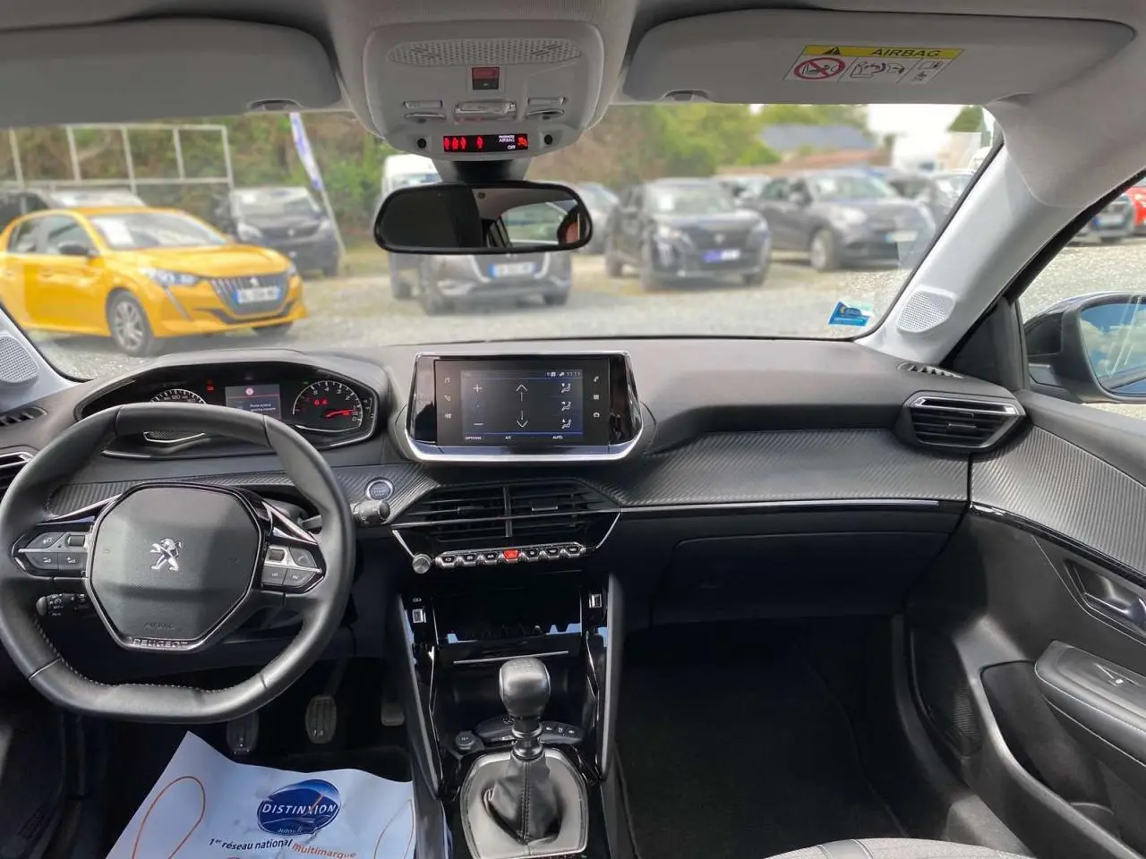 Intérieur noir de la Peugeot 208 2021, vue de face sur le tableau de bord avec écran tactile et volant multifonctions.