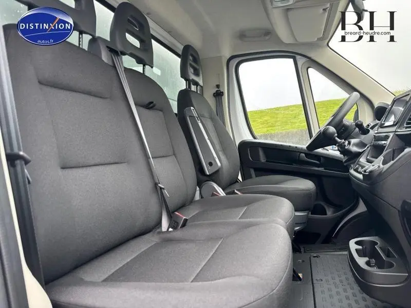 Vue intérieure côté conducteur du Fiat Ducato Benne 2023, sièges tissu noir et tableau de bord visible.