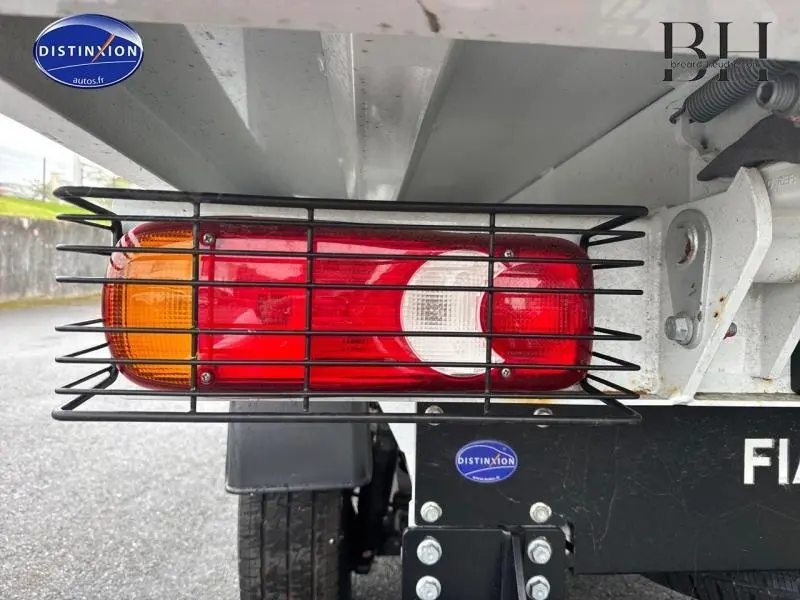 Gros plan sur le feu arrière protégé par une grille métallique du Fiat Ducato Benne blanc, côté arrière droit.