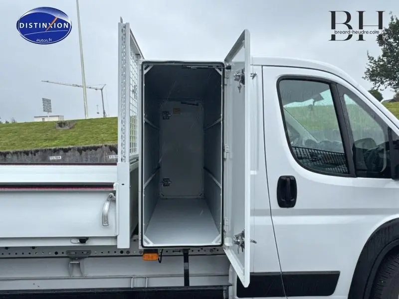 Vue latérale droite du FIAT Ducato Benne blanc 2023 avec la porte du grand coffre acier ouverte.