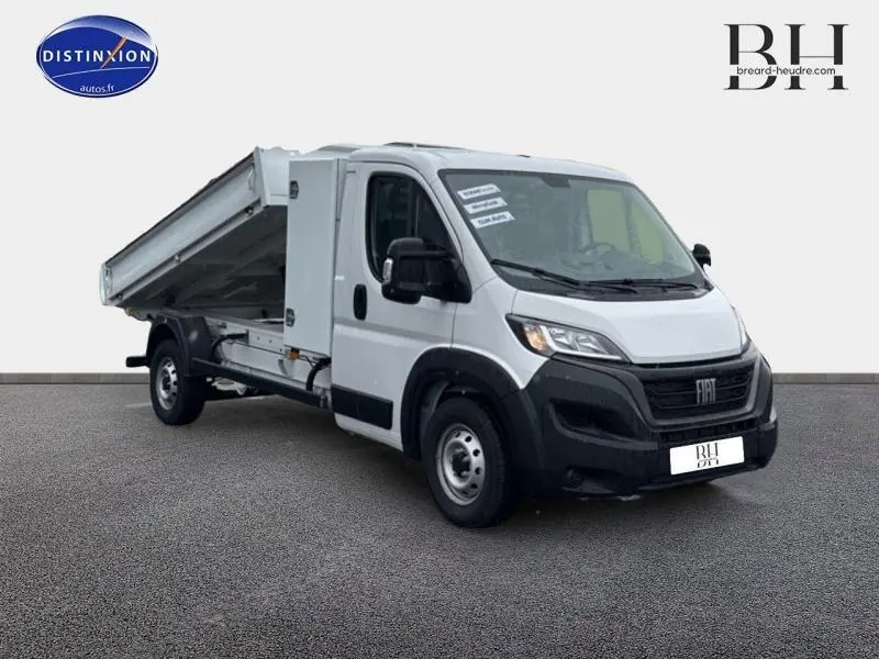 Fiat Ducato Benne blanc en 3/4 avant droit, benne acier relevée et cabine utilitaire visible sur fond neutre.