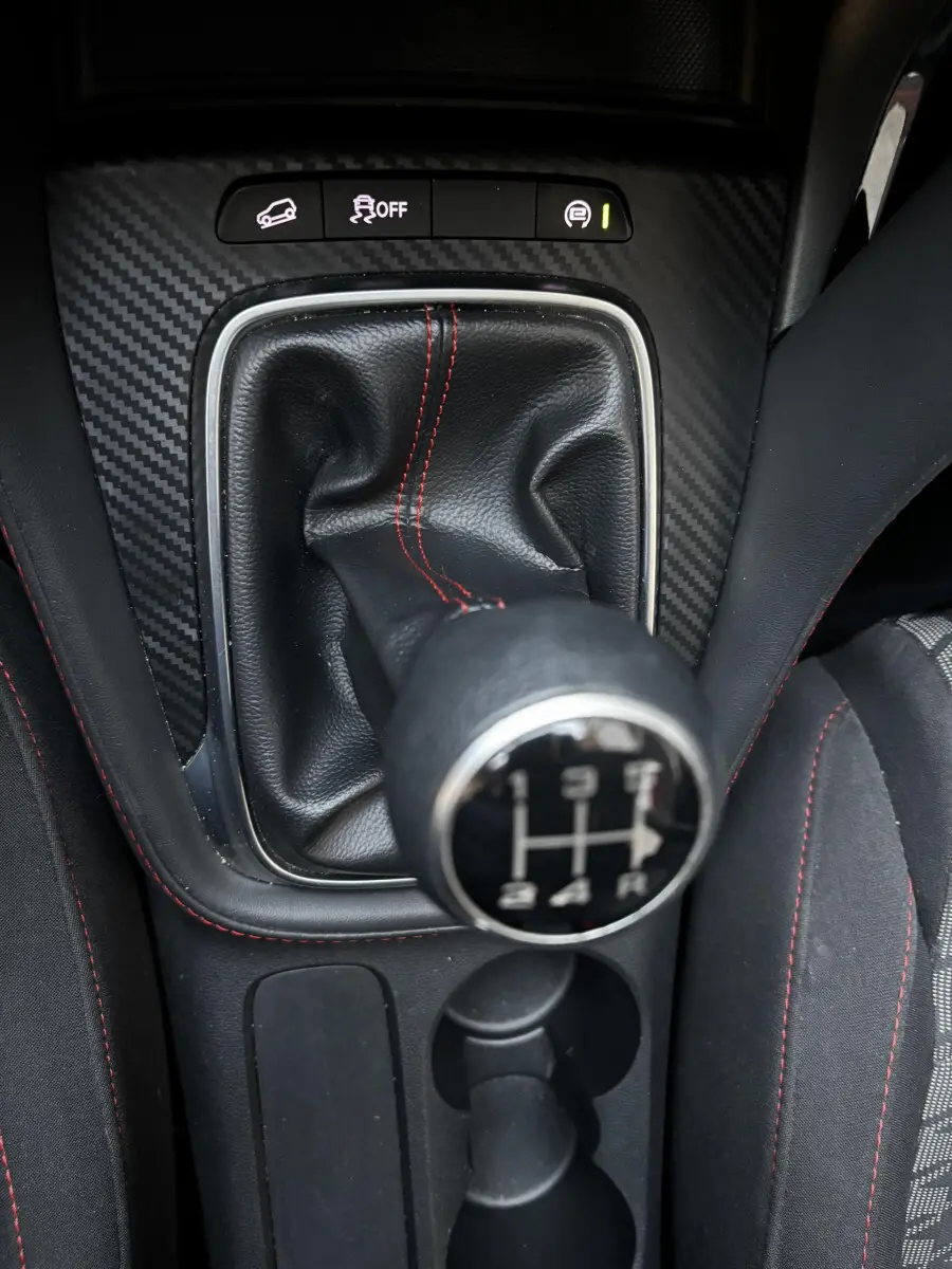 Le levier de vitesses manuel noir avec surpiqûres rouges du MG ZS 1.5L VTI-Tech, vue rapprochée intérieure.