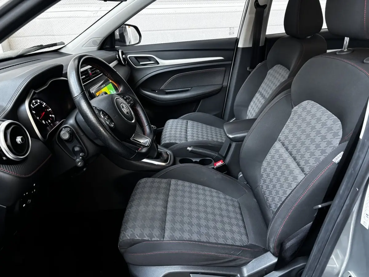 Intérieur avant droit du MG ZS gris clair 2022, sièges tissu à motif pied-de-poule et volant cuir multifonctions.