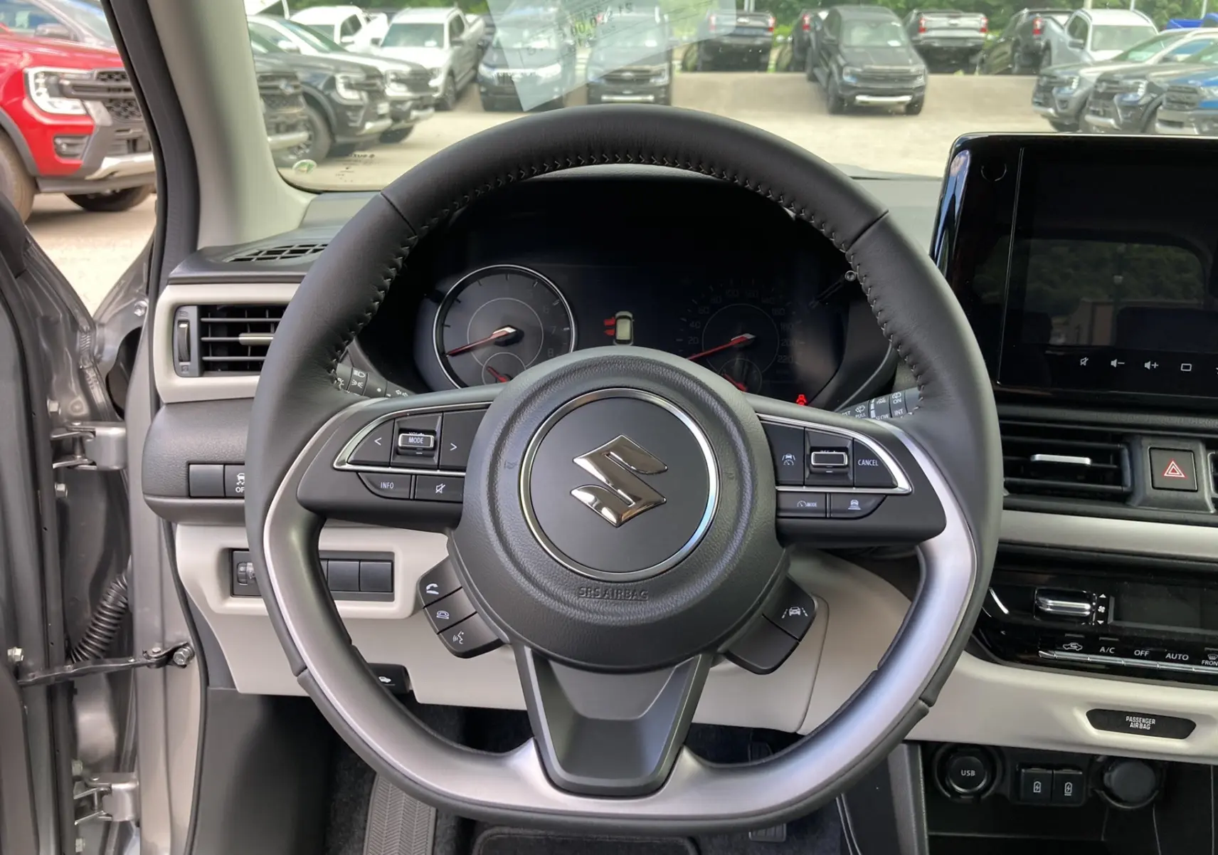 Vue centrée sur le volant cuir multifonctions d'une Suzuki Swift 2025 gris argent premium, tableau de bord et écran tactile visibles