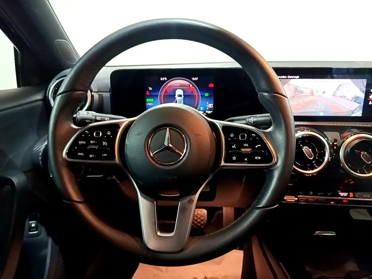 Vue intérieure centrée sur le volant cuir noir et le tableau de bord numérique de la Mercedes Classe A 250 e Business Line.