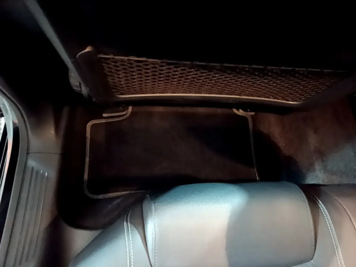 Détail du coffre arrière avec filet de rangement et tapis noir dans une Mercedes Classe A A 250 e Business Line 2020.