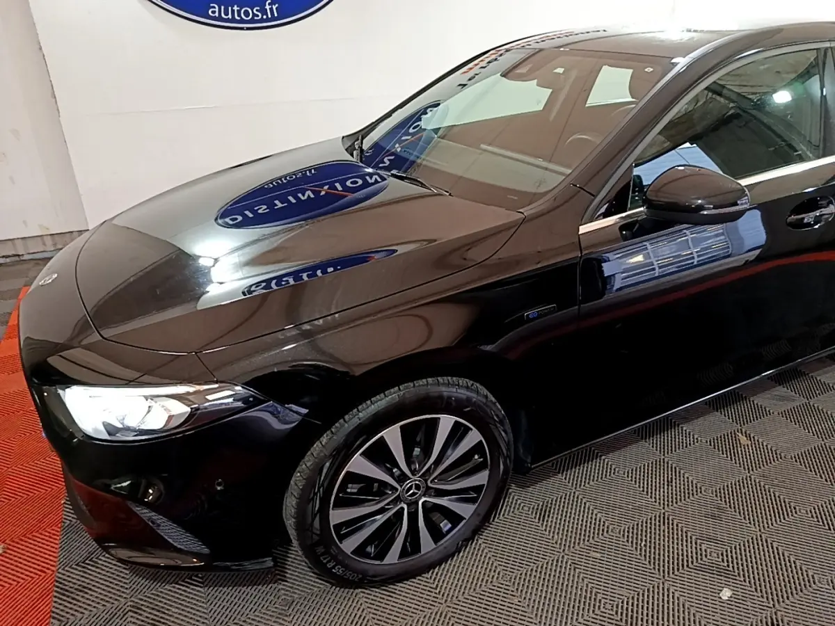 Vue 3/4 avant gauche d'une Mercedes Classe A 250 e Business Line noire avec jantes alliage et phares LED allumés.