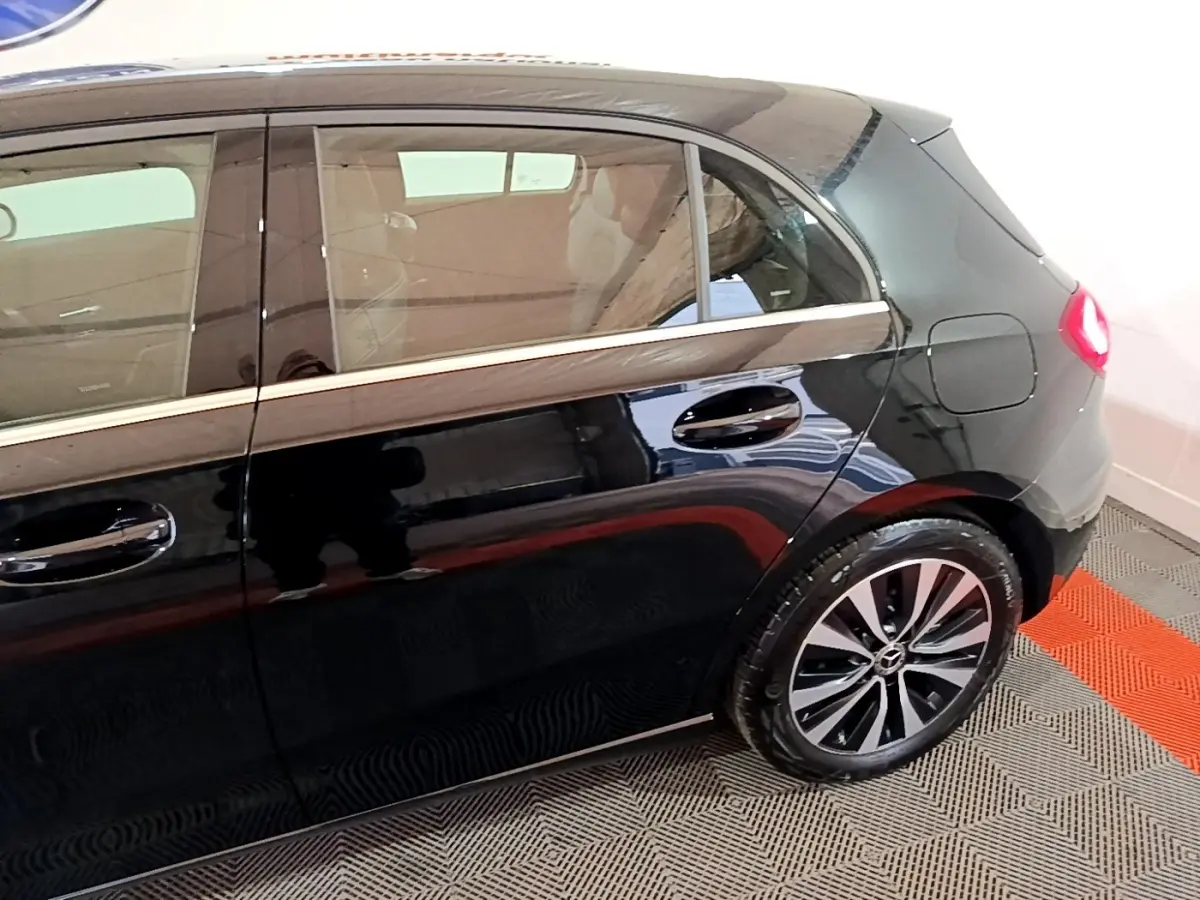 Vue latérale droite d'une Mercedes Classe A 250 e Business Line noire, mettant en valeur la porte arrière et la roue arrière.
