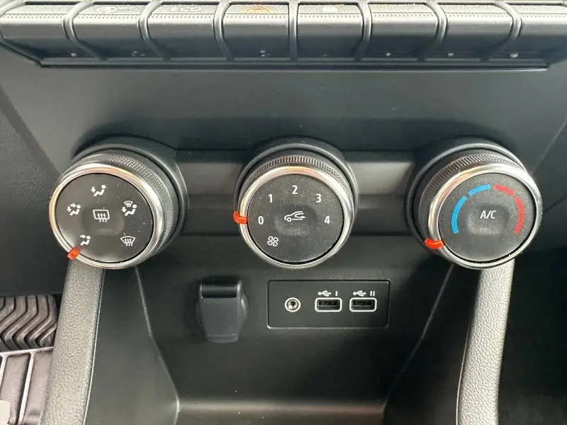 Gros plan sur les commandes manuelles de climatisation de la Renault Clio 2025 gris Rafale, avec ports USB et prise auxiliaire.