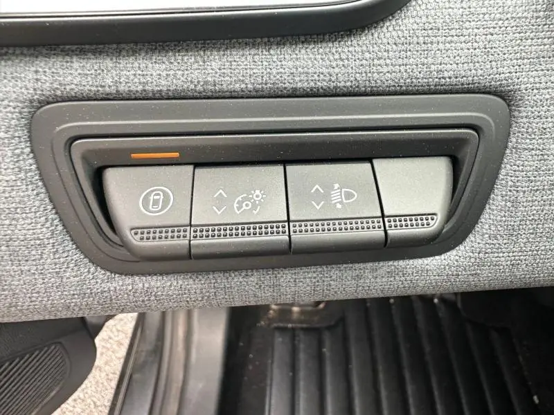 Gros plan sur les boutons de réglage d’éclairage et verrouillage intérieur, sur tissu gris dans Renault Clio 2025.
