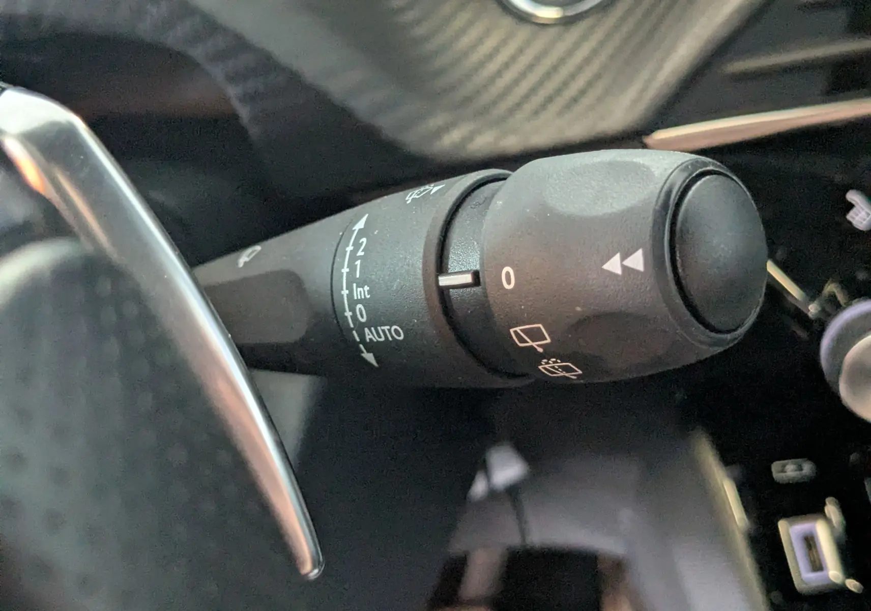 Gros plan sur la manette de commande des essuie-glaces dans l’habitacle d’une Peugeot 208 Hybrid 145 gris selenium.