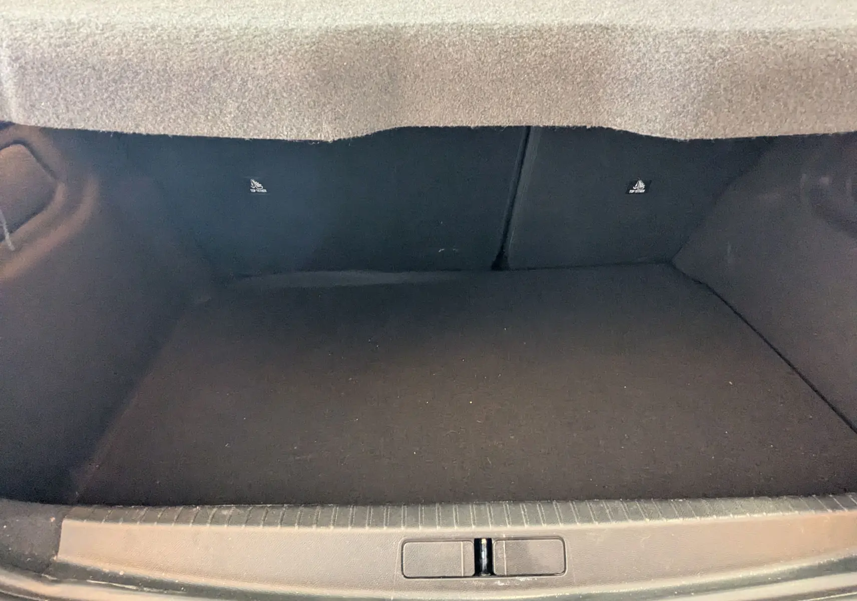 Coffre vide vu de face du Peugeot 208 Hybrid 145 e-DCS6 GT, intérieur noir, sans chargement visible.
